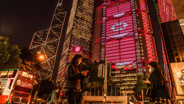 Pedestrians pass the illuminated HSBC headquarters  in Hong Kong. The bank is caught up in China and US tensions.