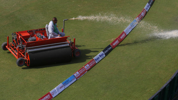 A groundskeeper empties the super sopper at the cricket.