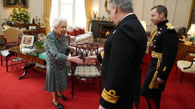 Queen Elizabeth speaking with Rear Admiral James Macleod (right) and Major General Eldon Millar at Windsor Castle on February 16. While using a walking stick, she quipped: “As you can see, I can’t move.”