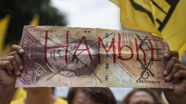A protester in Venezuela holds a fake banknote with the word "Hungry" written on it in 2016.