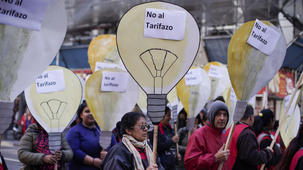 People hold cutouts of light bulbs with words that read in Spanish "no to the price hike" on Wednesday in Buenos Aires.