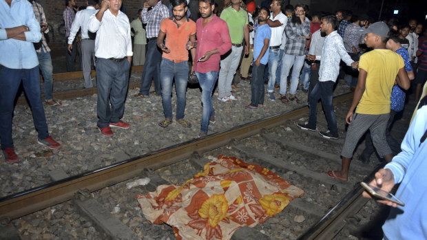 The body of a victim of a train accident lies covered in cloth on a railway track in Amritsar, India, on Friday.