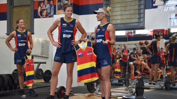 Jess Foley (centre) is presented with her Adelaide Crows jumper by teammate Erin Phillips (right).