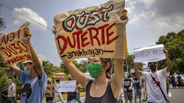 Protesters wearing masks hold up placards as they protest an anti-terror bill in the Philippines.