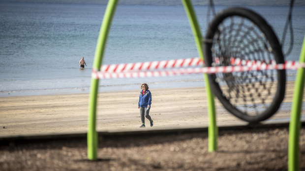 A woman walks past a closed off playground in Auckland.