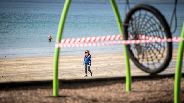 A woman walks past a closed off playground in Auckland.