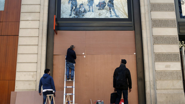 Workers reinforce store windows on the Champs-Elysees to prepare for an expected protest by the "yellow jackets".