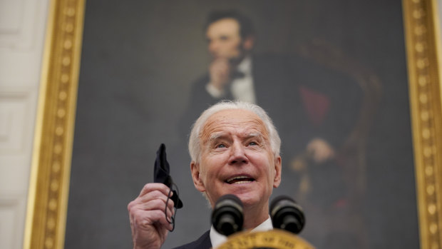 US President Joe Biden holds a protective mask while outlining his administration's Covid-19 response. 