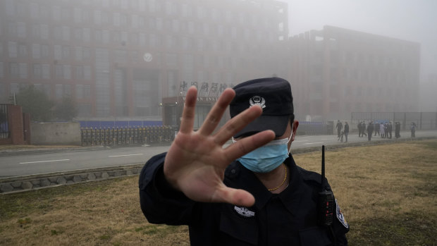 A security guard moves journalists away from the Wuhan Institute of Virology as the WHO team arrives for a field visit in February.