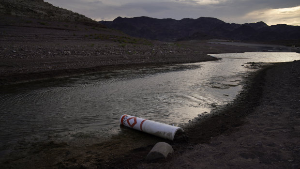 A buoy once used to warn of a submerged rock rests on the ground along the waterline near a closed boat ramp on Lake Mead at the Lake Mead National Recreation Area.