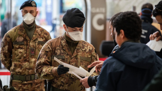 Italian soldiers process passengers leaving from Milano Centrale train station.