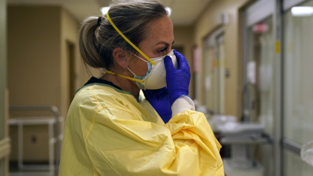 Registered nurse Chrissie Burkhiser puts on personal protective equipment as she prepares to treat a COVID-19 patient in the emergency room at Scotland County Hospital in Memphis, Missouri.