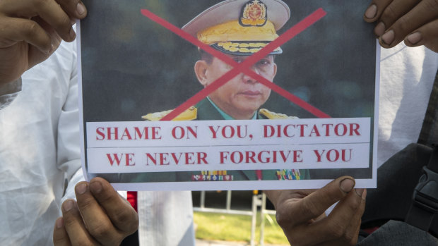 Myanmar nationals living in Thailand hold a picture denouncing Myanmar military Commander-in-Chief Senior General Min Aung Hlaing during a protest in front of the United Nations’ building in Bangkok, Thailand.