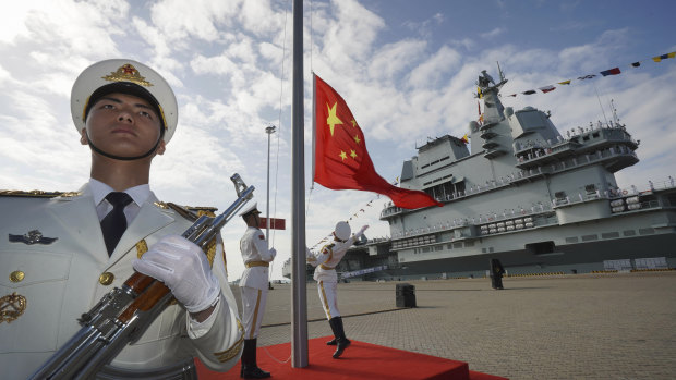 On the rise: guards raise the Chinese flag during the commissioning ceremony of China's Shandong aircraft carrier at a naval port in Sanya last year.