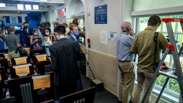 Members of the media look outside from the Briefing Room at the White House.