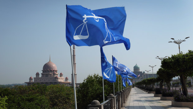 Campaign flags for the Barisan Nasional party fly as the Putra Mosque, left, stands in the background in Putrajaya, Malaysia, on Friday.
