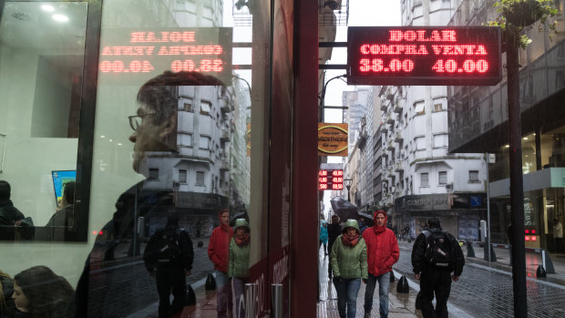 A sign displaying US dollar exchange rates hangs as people wait inside of a currency exchange house in Buenos Aires, Argentina. Argentina's currency crisis intensified last week as the peso plunged 20 per cent.