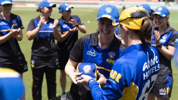 Anna Lanning is presented with her ACT Meteors cap by captain Erin Osborne.