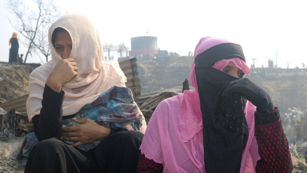 Rohingya refugees cry sitting at the site of the fire. 