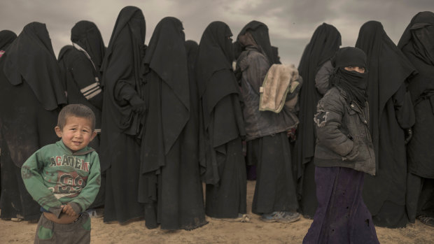 Women and children stand in line at a reception area for people evacuated from the last shred of territory held by Islamic State.