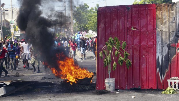 Haitians walk near a burning barricade  in Port-au-Prince.