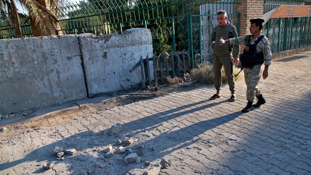Security forces inspect the scene of the rocket attack at the gate of al-Zawra public park in Baghdad, Iraq.