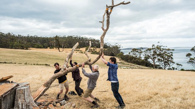 Kevin Perkins (second from right) and helpers affix an old tree to a stump, which will serve as the setting for 12 whittled bird sculptures. 