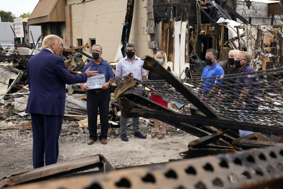 US President Donald Trump talks with owners of destroyed businesses as he tours an area damaged after a police officer shot Jacob Blake in Kenosha.