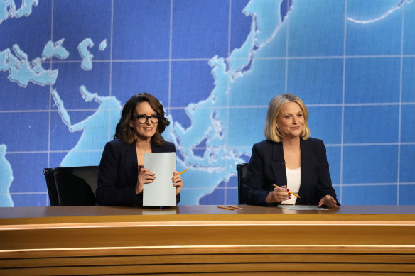 Tina Fey and Amy Poehler behind the SNL news desk.