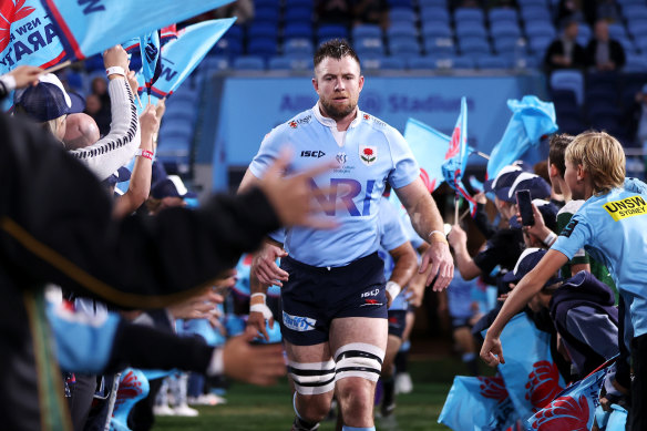 Waratahs star Jed Holloway runs through a tunnel with juniors cheering on.