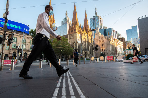 Early morning commuters near Flinders Street station on the first day back after a snap five-day lockdown.