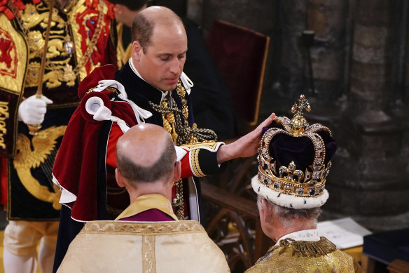 Prince William touches St Edward’s Crown on King Charles III’s head.