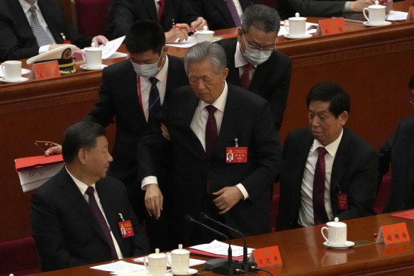 Former Chinese President Hu Jintao, centre, is shuffled away.
