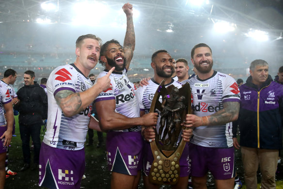 Justin Olam with Storm teammates and the premiership trophy in 2020.