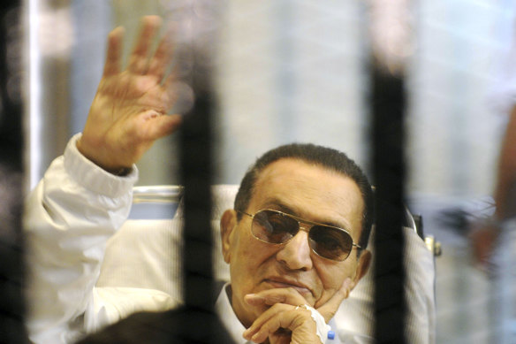 Hosni Mubarak waves to his supporters from behind bars as he attends a hearing in his retrial on appeal in Cairo in 2013.
