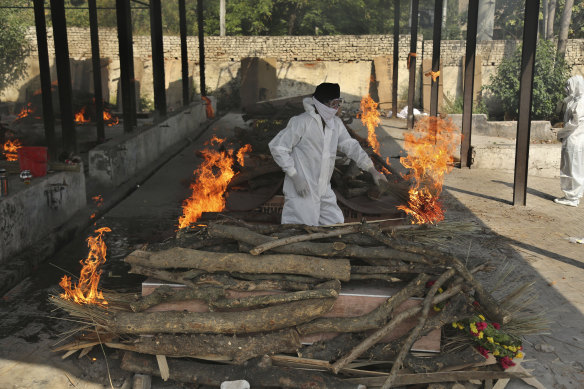 A family member performs the last rites of a COVID-19 victim at a crematorium in Jammu, India, on Friday.