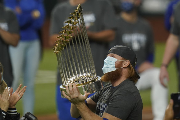 Justin Turner, who was pulled in the eighth inning after testing positive for coronavirus, celebrates with the trophy.