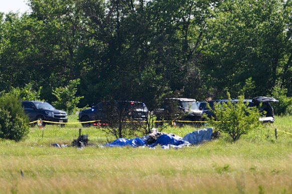 Part of the wreckage of a plane crash is covered with a blue tarp.