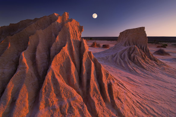 The full moon rises while the sun sets simultaneously at the ancient sandstone Walls of China at Mungo National Park.