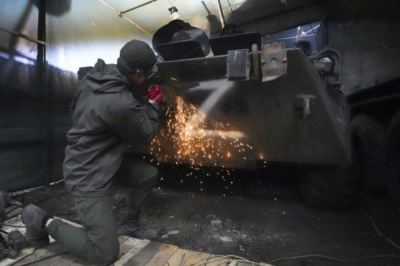 A Ukrainian National Guard soldier cleans away a Z letter, a sign of the Russian army, from a captured Russian tank in the outskirts of Kharkiv.