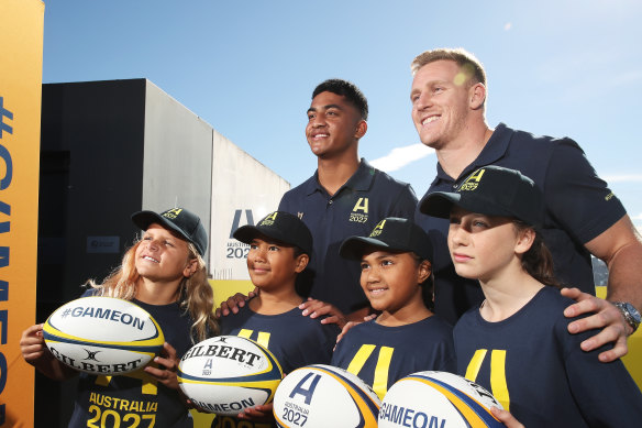Waratahs player Clem Halaholo (left) and Wallaby player Reece Hodge (right) pose with young players at the launch of Australia’s Rugby World Cup 2027 bid.