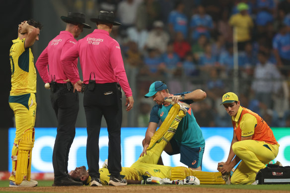 Glenn Maxwell is treated by Australian physiotherapist Nick Jones and 12th man Sean Abbott after collapsing with cramp.