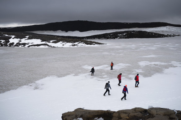 People walk on snow atop the Ok volcano crater on their way to the ceremony to mark the demise of the Okjokull glacier. 