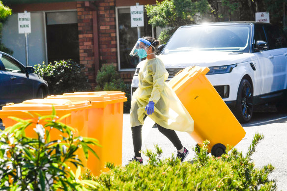 A staff member in protective gear disposes of waste at Estia Health in Keilor Downs on Monday.