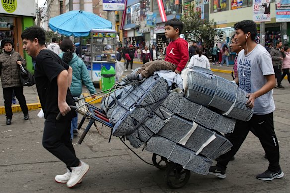 Stuart Rodriguez gets a ride on a dolly of jean fabric bought at the Gamarra textile market as his brothers Steve and Stevenson transport the load to their father’s factory in Lima, Peru.
