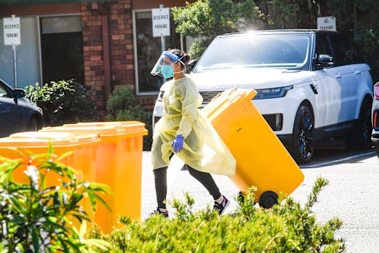 A staff member in protective gear disposes of waste at Estia Health.
