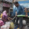 Containers are filled from a water tanker in a New Delhi slum this month.