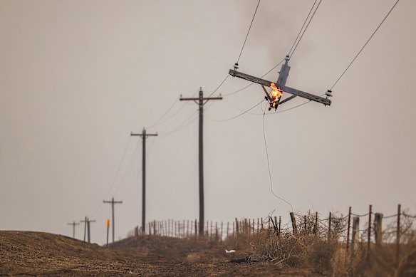 Part of a telephone pole is suspended as it burns from the Smokehouse Creek Fire in Canadian, Texas.