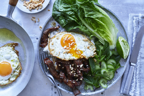 Beef stir-fry with fried egg and peanuts.