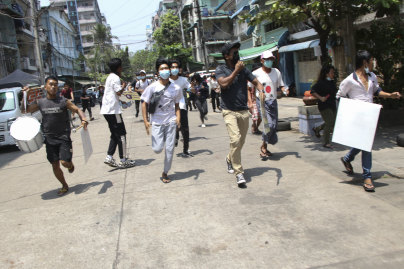 Protesters run to avoid security forces in Yangon.